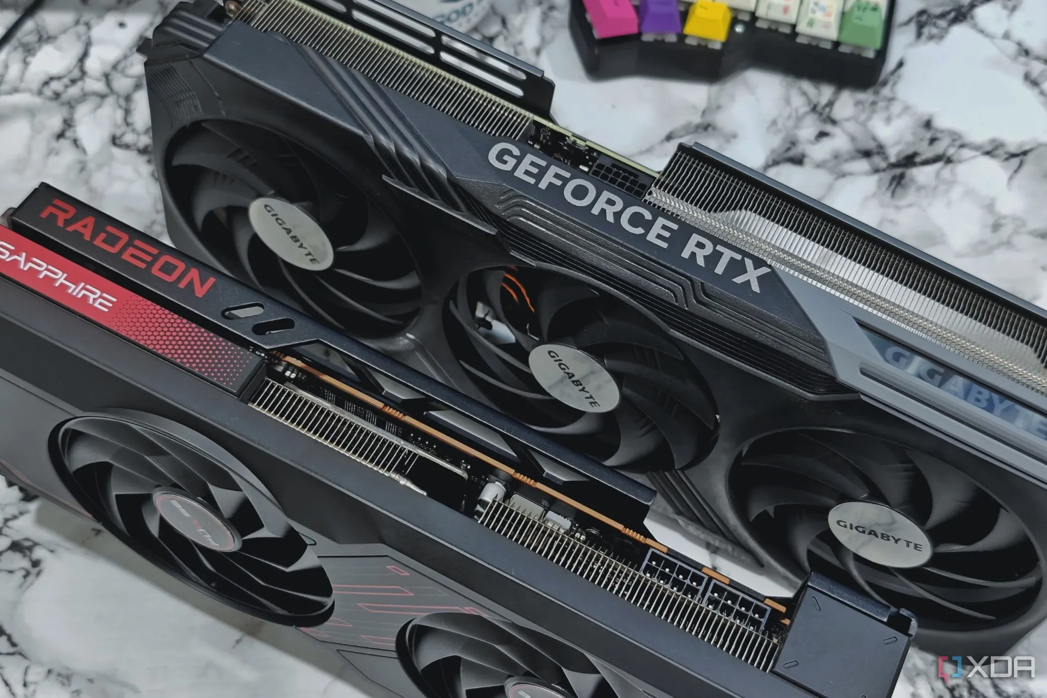 Card đồ họa GeForce RTX 4070 Ti và Radeon 7700XT đặt trên bàn cạnh bàn phím cơ