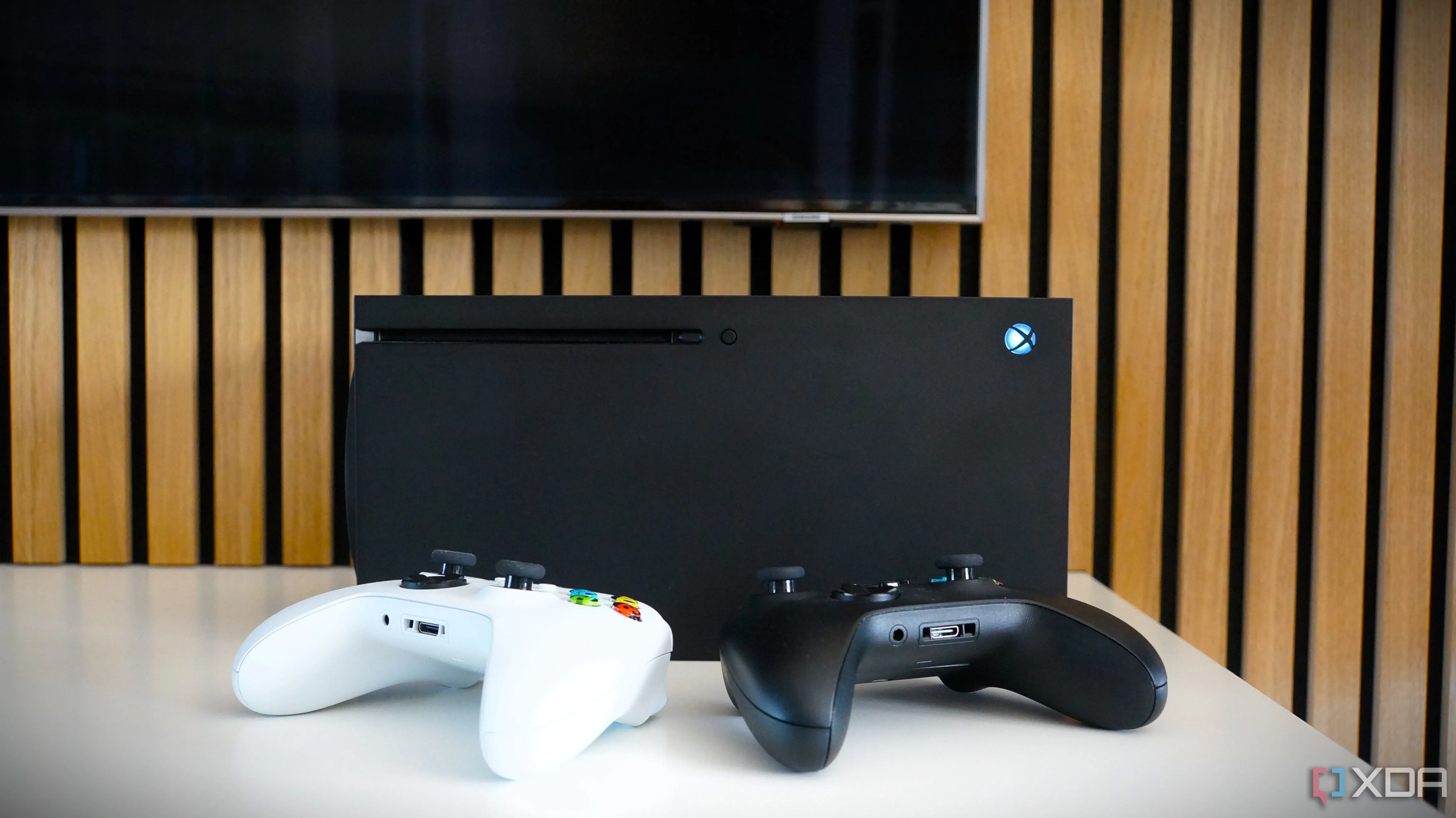 Chiếc TV Samsung hiển thị màn hình điều khiển của Xbox Series X, cùng với console và tay cầm chơi game đặt phía trước, tượng trưng cho trải nghiệm chơi game bị gián đoạn do sự cố server.