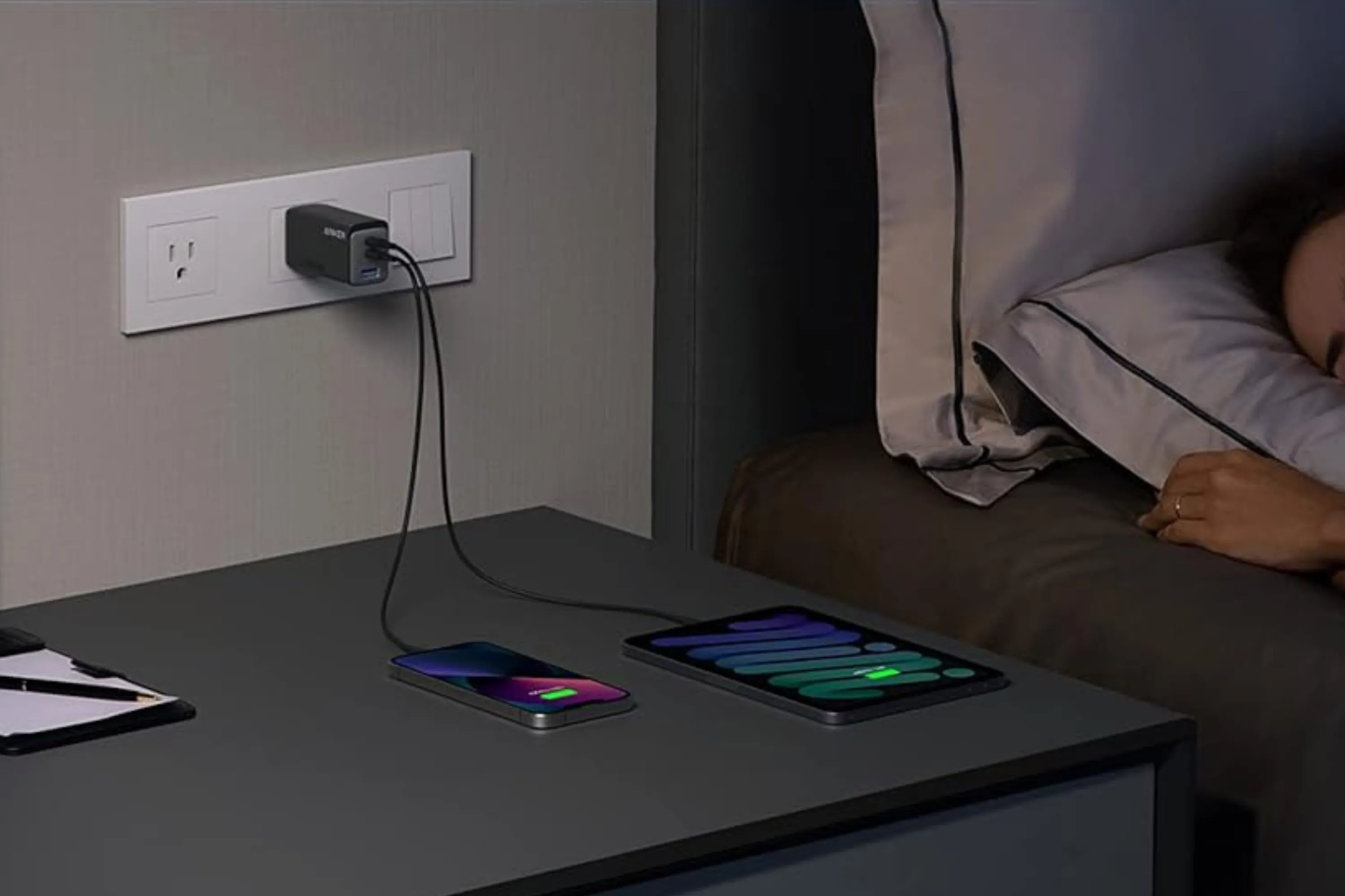 Củ sạc Anker 735 đang sạc cùng lúc máy tính bảng và điện thoại trên tủ đầu giường