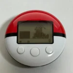 Hình ảnh thiết bị PokeWalker màu đỏ hiển thị Pokémon Dragonite trên màn hình.