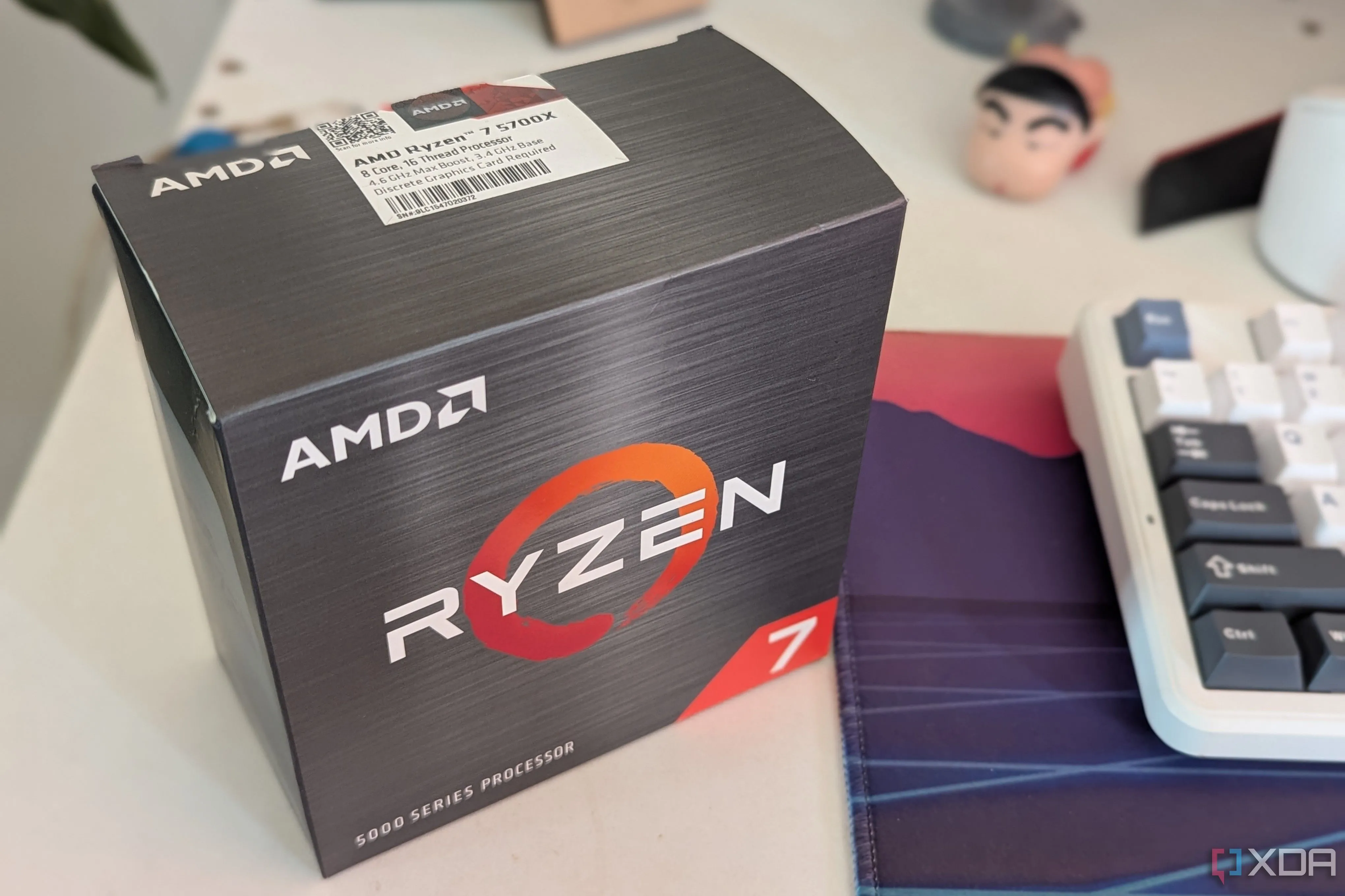 Hộp CPU AMD Ryzen 7 5700X đặt trên bàn làm việc cạnh bàn phím và tấm lót chuột