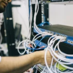 Kỹ sư IT đang kết nối cáp mạng Ethernet vào thiết bị chuyển mạch để cấu hình hệ thống tường lửa