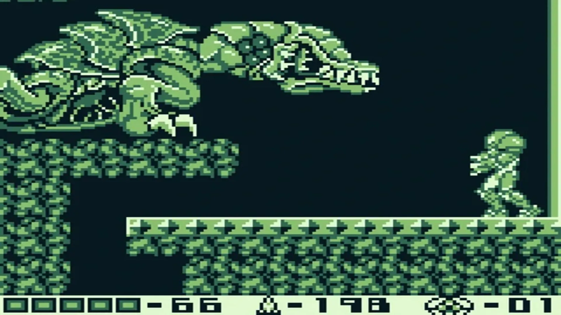 Màn hình chơi game từ Metroid II: The Return of Samus trên Game Boy, hiển thị Samus trong bộ Power Suit chiến đấu trong một môi trường tối tăm, đơn sắc.