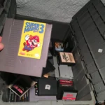 Người chơi lấy băng game Super Mario Bros 3 từ hộp trò chơi retro cũ, tượng trưng cho việc khám phá lịch sử game