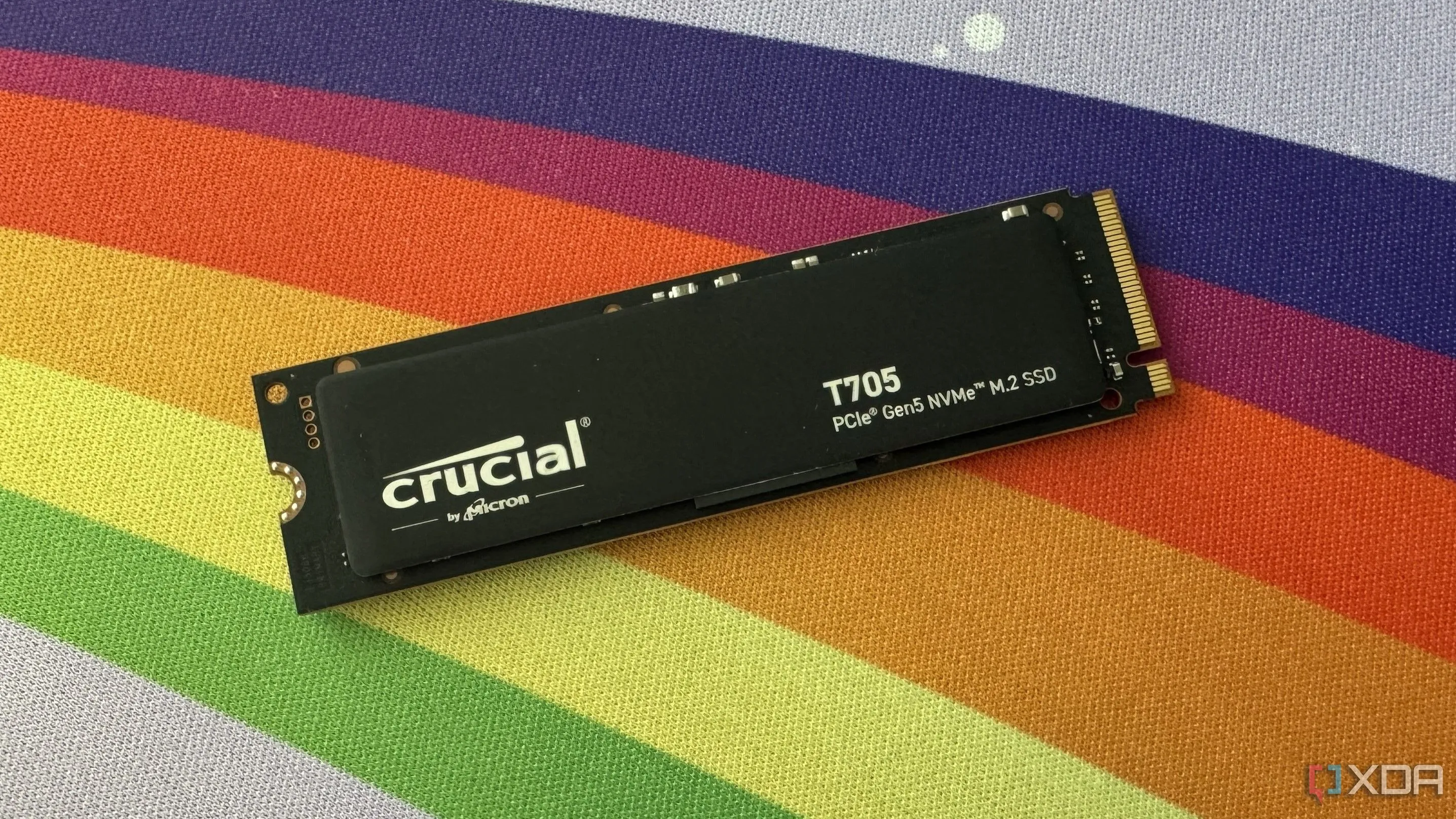 Ổ cứng SSD Crucial T705 Gen5 NVMe trên bàn di chuột cầu vồng, minh họa tốc độ cao